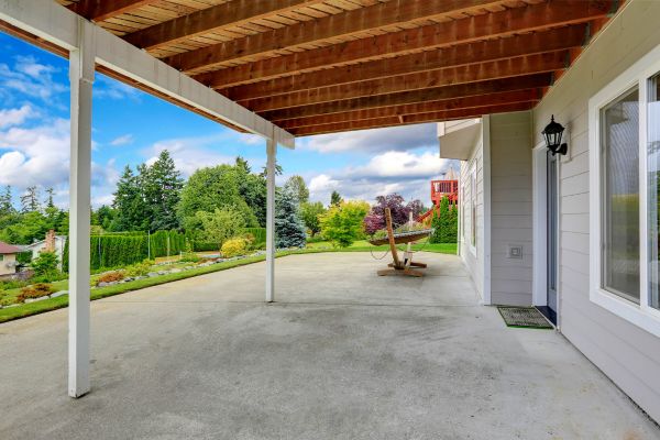 a patio with a swing and trees in the background